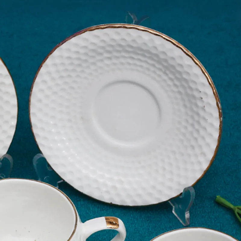 Close-up of a white textured saucer with gold edging