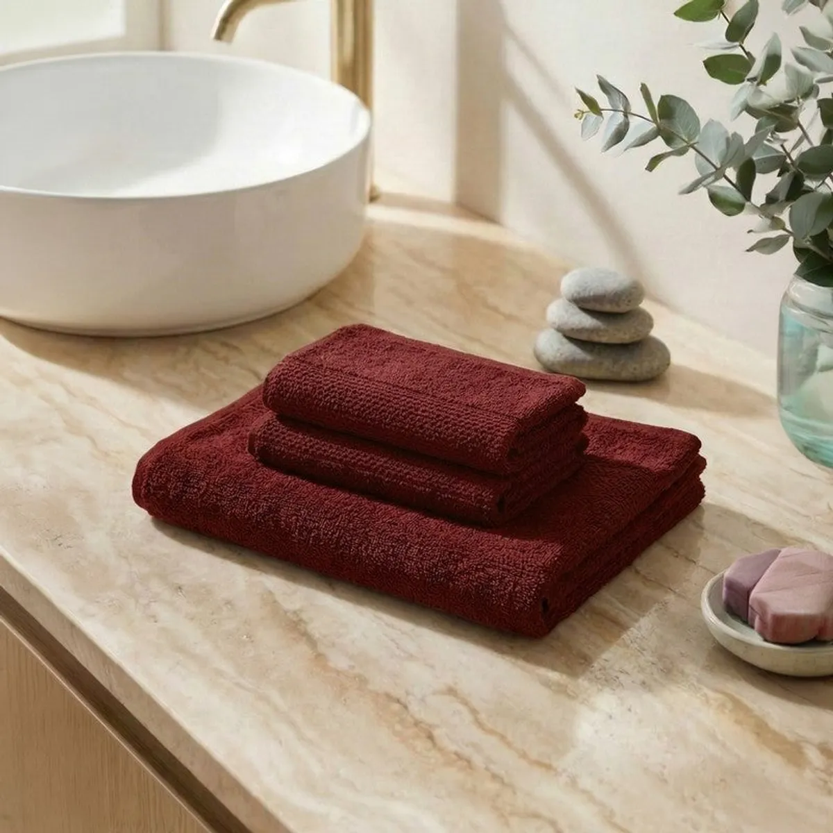 Folded brown bath towel and two hand towels arranged on a bathroom counter