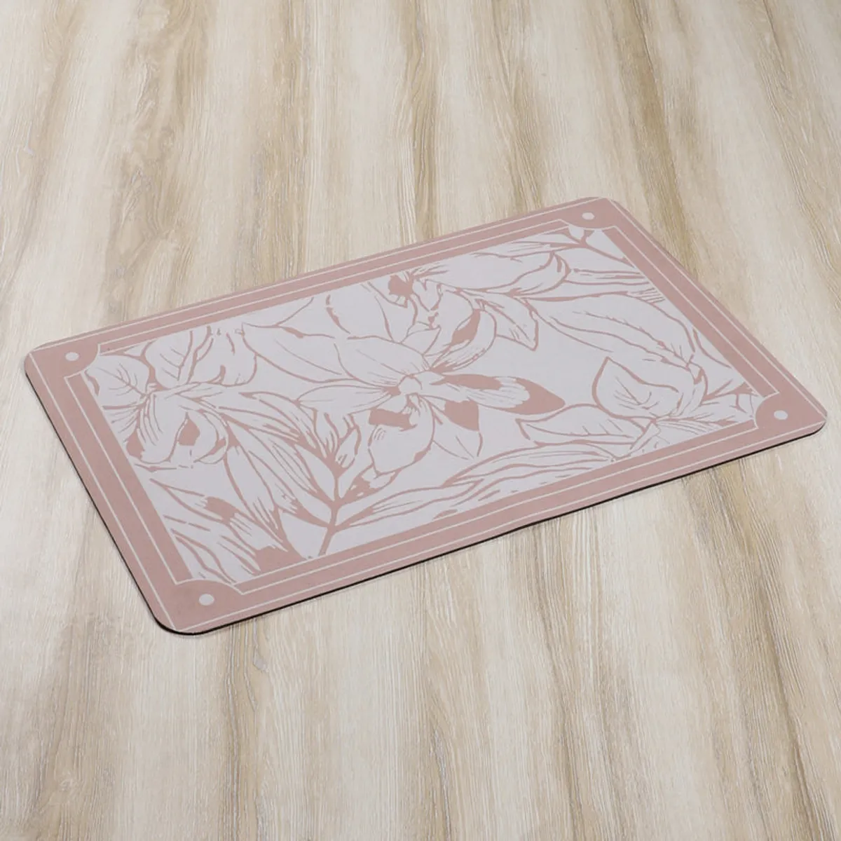 Close view of the peach and grey floral bath mat on a wood floor.