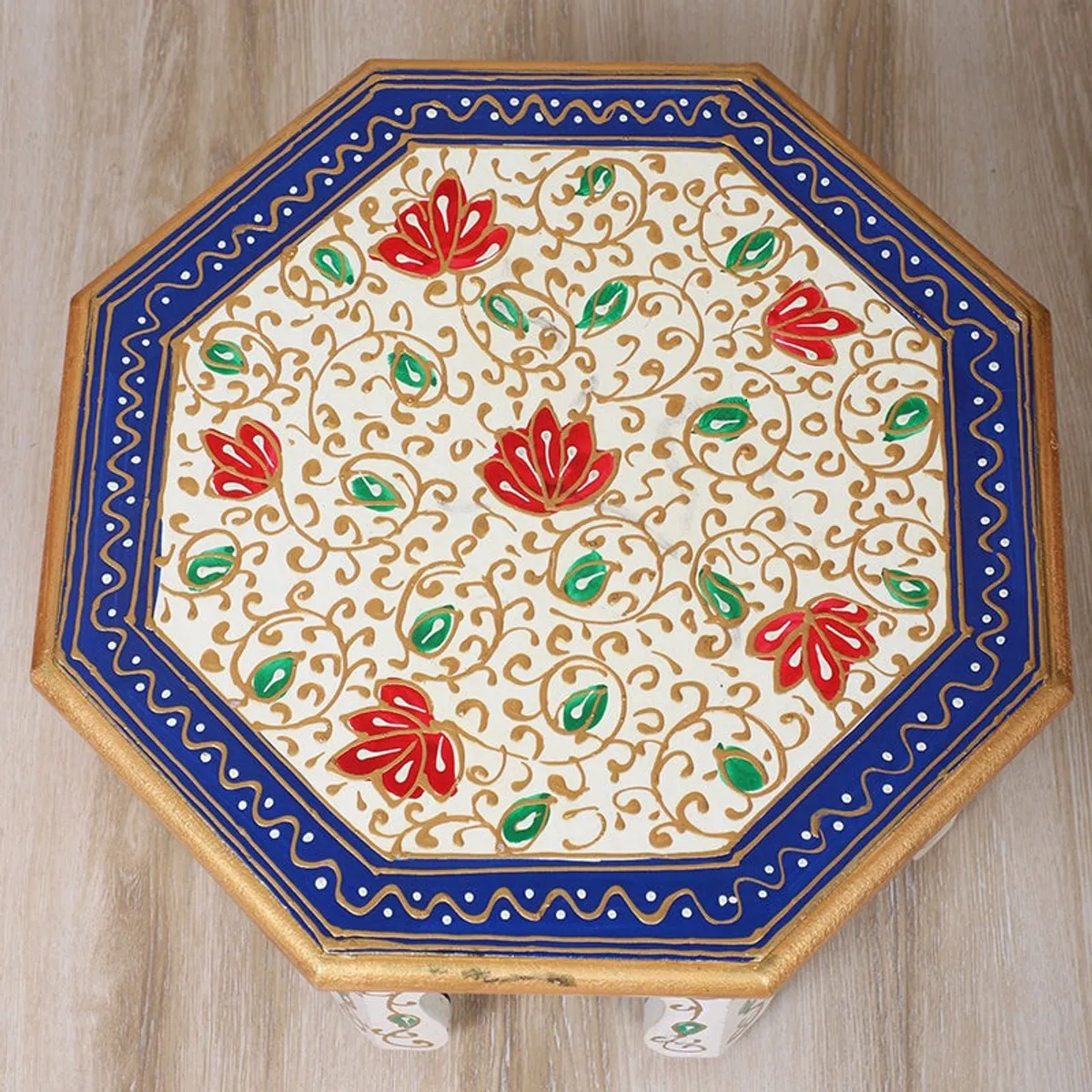 Close-up of the stool top showing blue border and red and green floral motifs