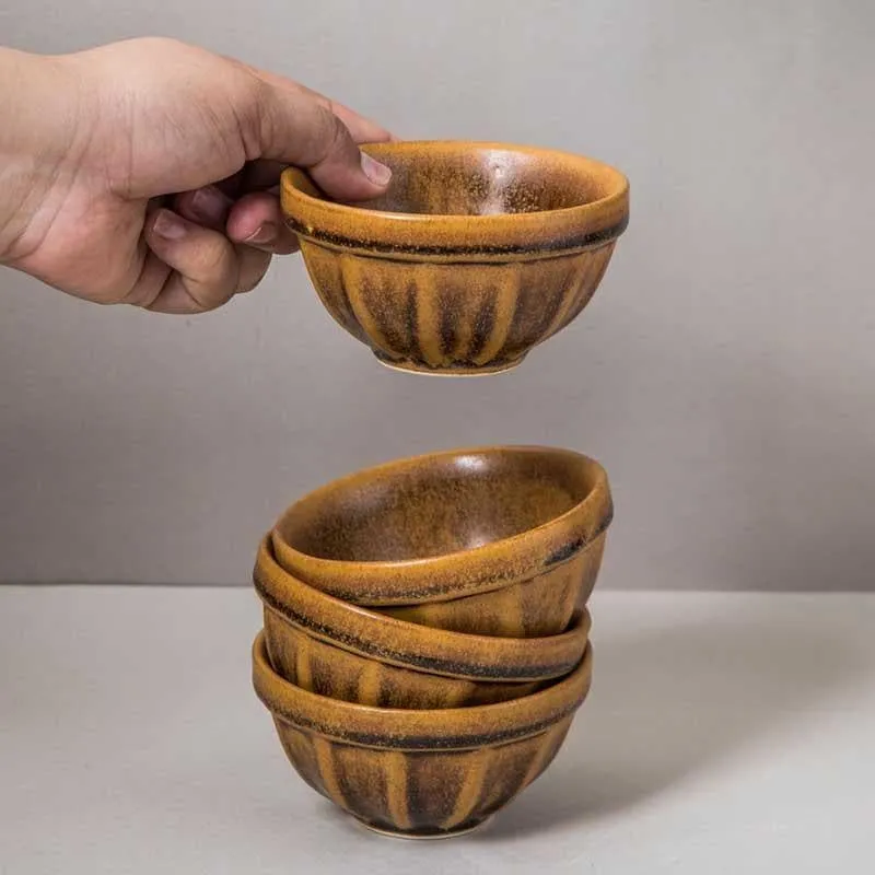 Brown snack bowl held in hand above a stack of matching bowls