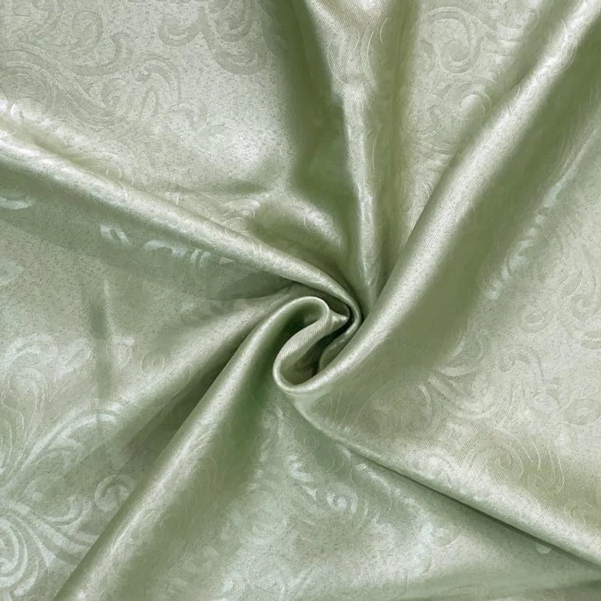 Detail of lustrous green jacquard curtain fabric gathered into soft folds