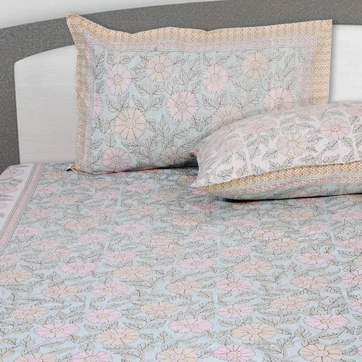 Floral bedsheet and pillow covers showing delicate pink flowers on a pale blue ground