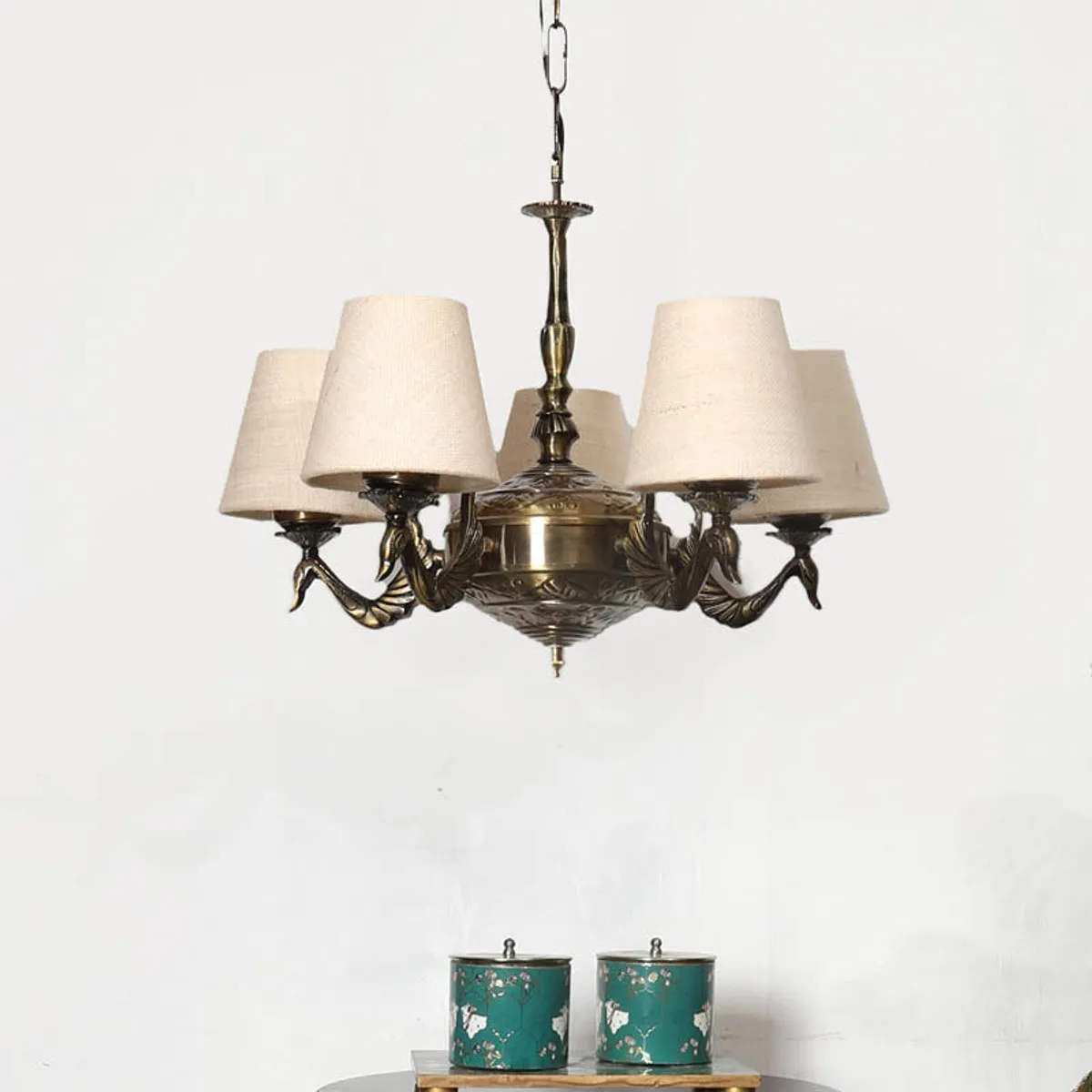 Antique brass ceiling lamp with beige shades hanging above a small console