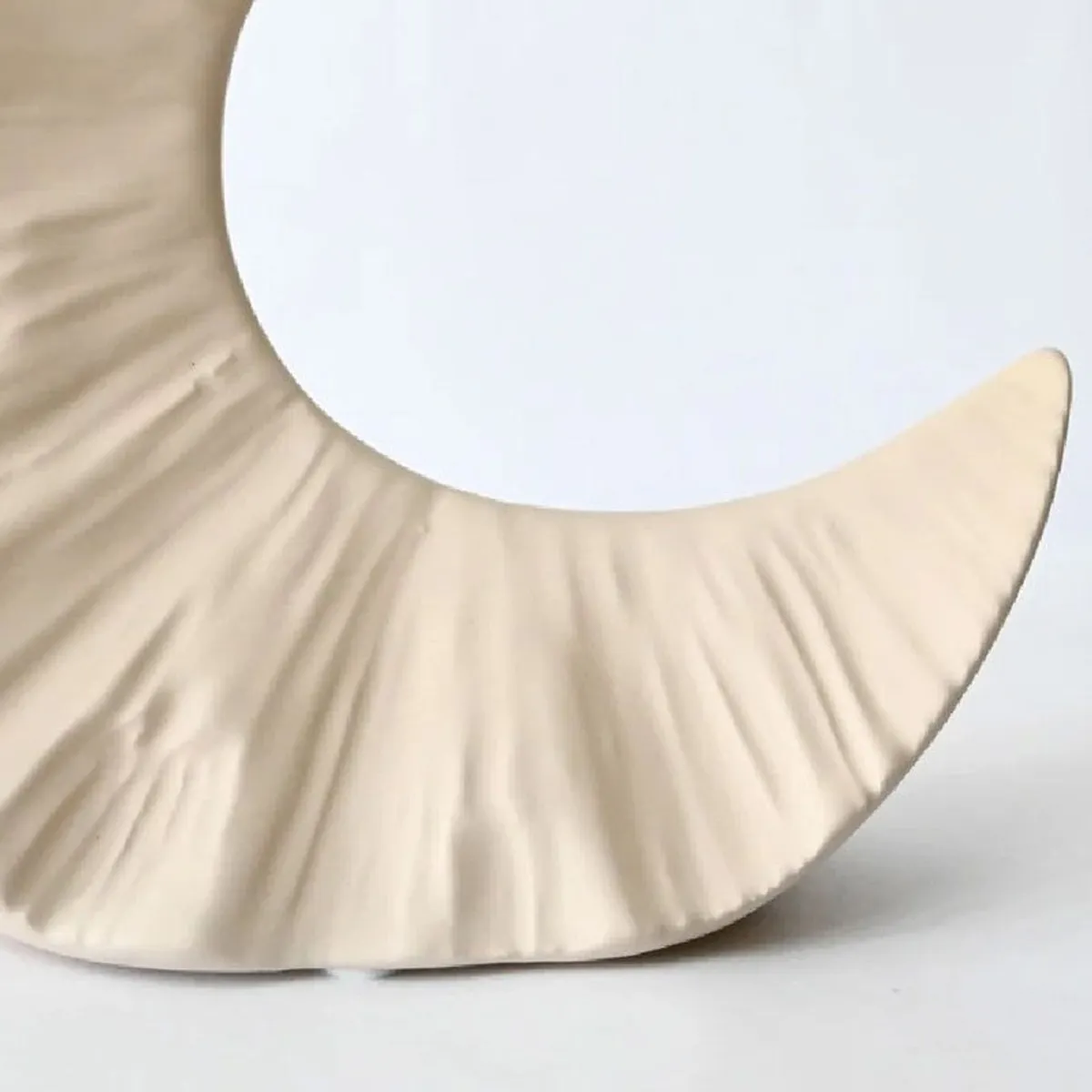 Close-up of the textured lower curve of the beige vase