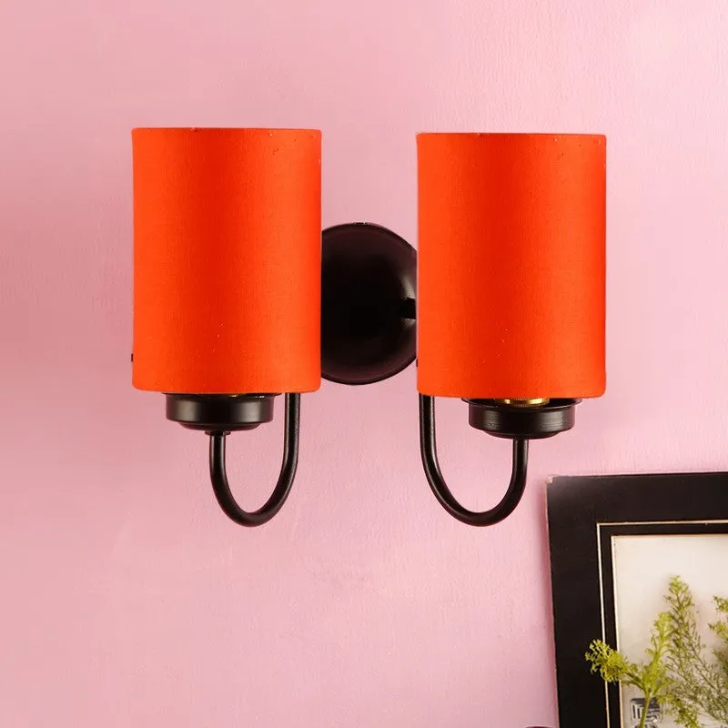 Orange cylindrical twin-shade wall lamp on a pink wall