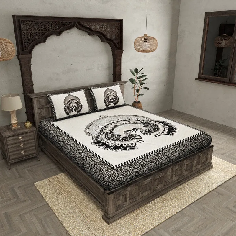 Black and white peacock print bedsheet with matching pillow covers on a wooden bed