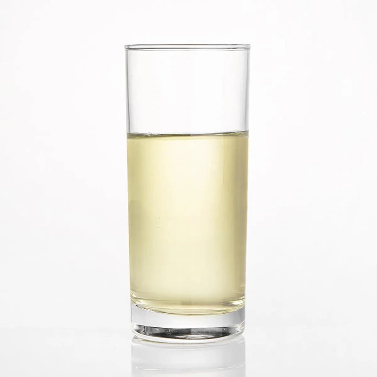 Clear cylindrical tumbler filled with a pale drink on a white background