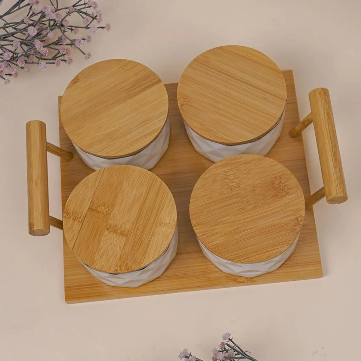 Top view of four white jars with bamboo lids on a rectangular bamboo tray