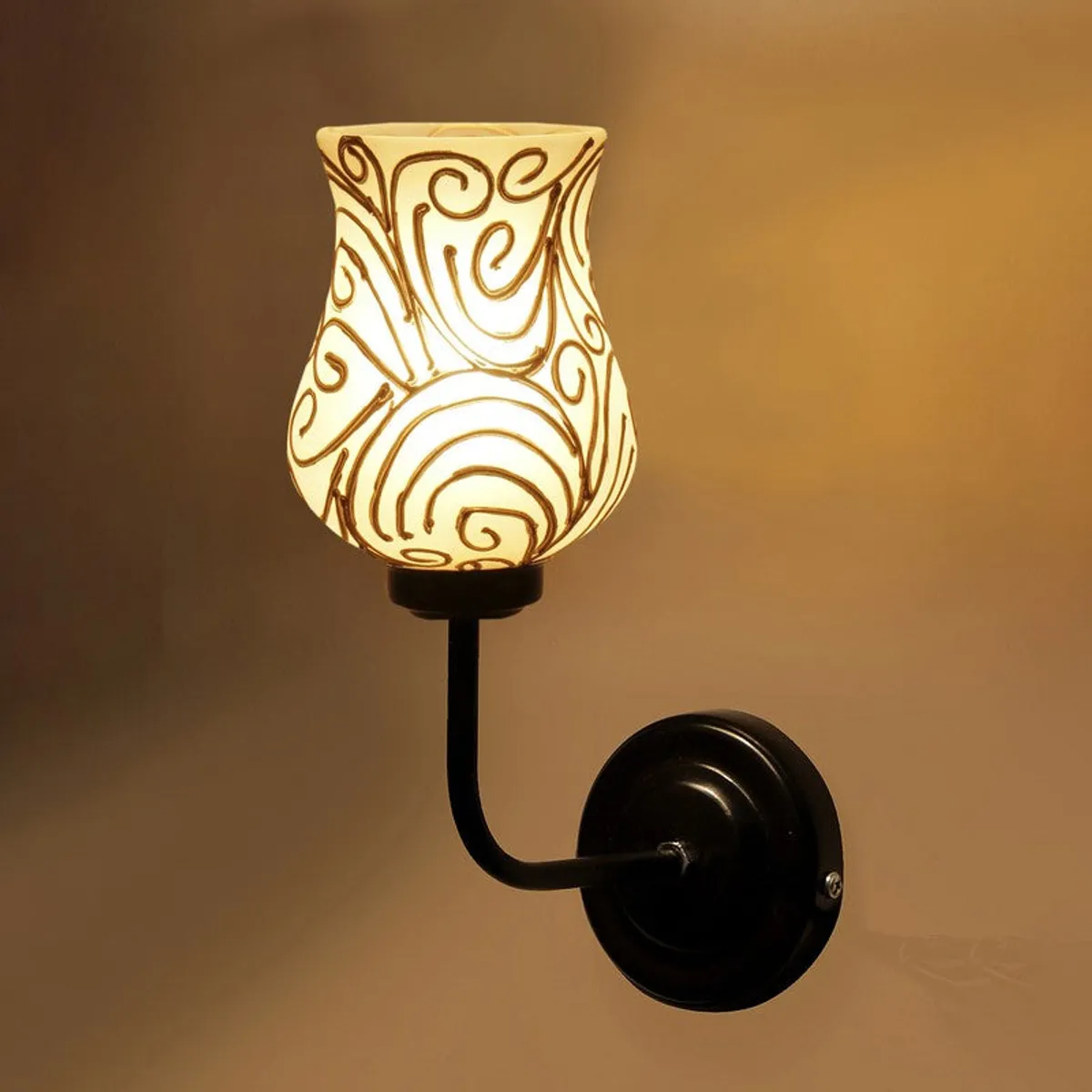 Close-up of illuminated glass wall lamp with gold swirls