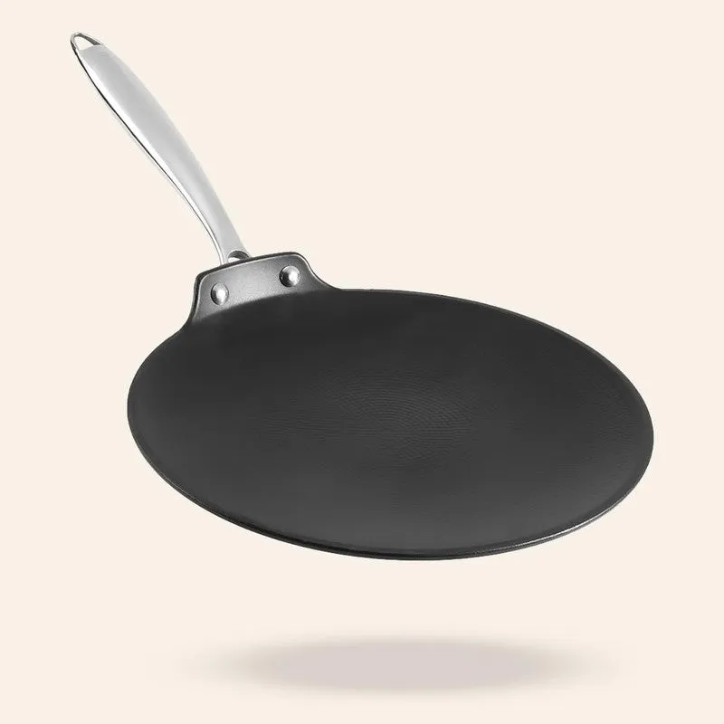 Black round roti tawa with a silver handle on a beige background