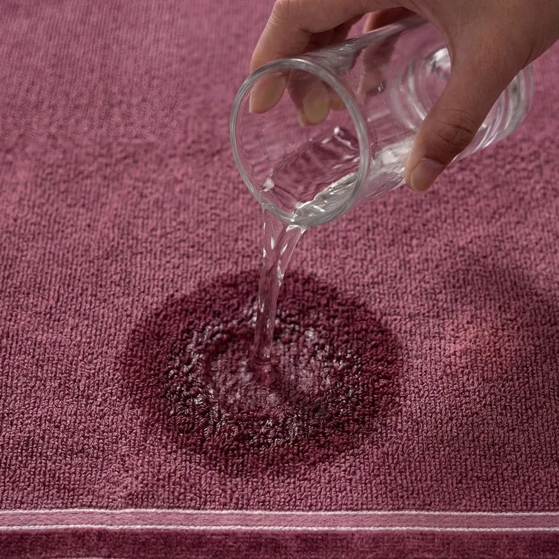 Water being poured onto the textured maroon towel surface