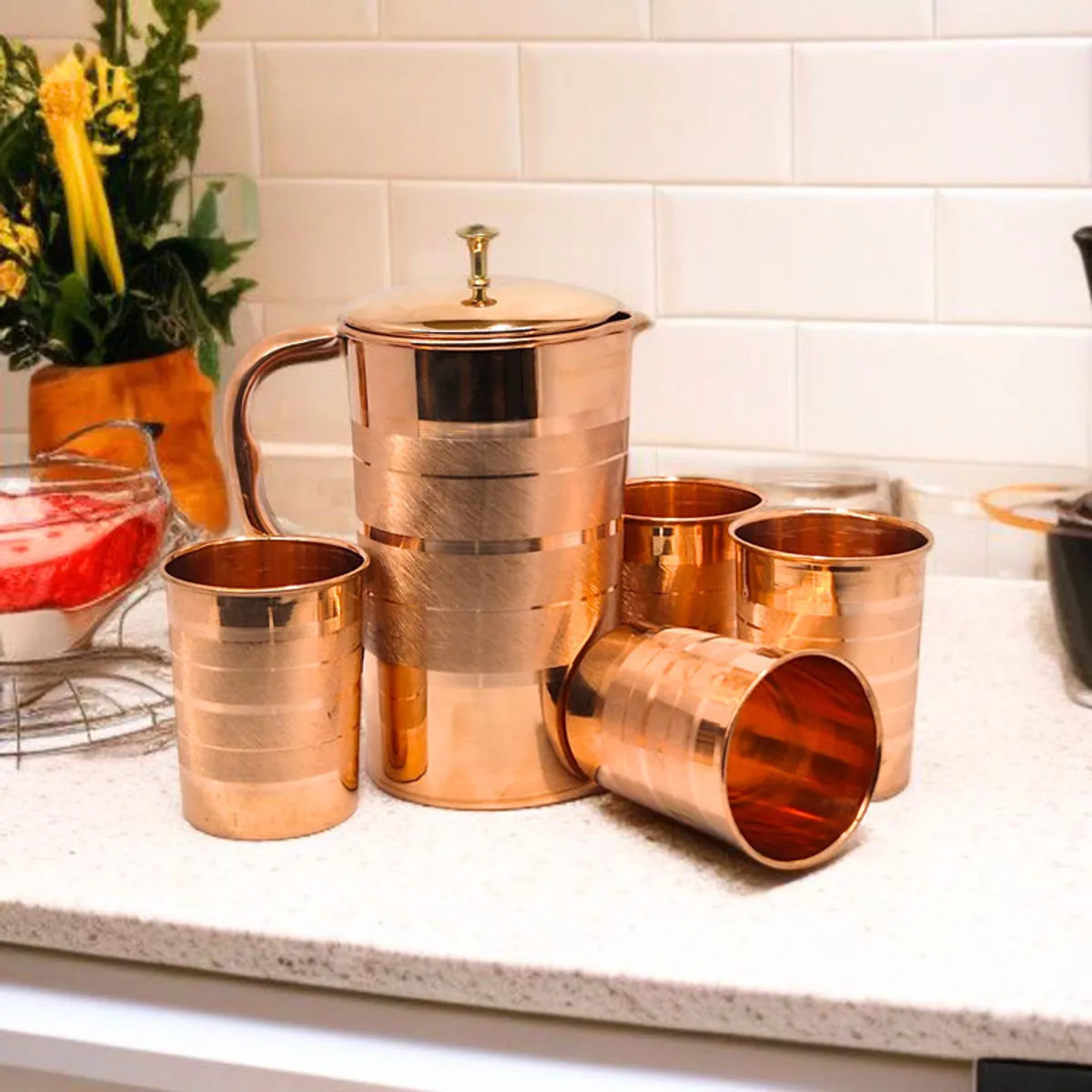 Copper five-piece jug and glass set arranged on a light kitchen worktop