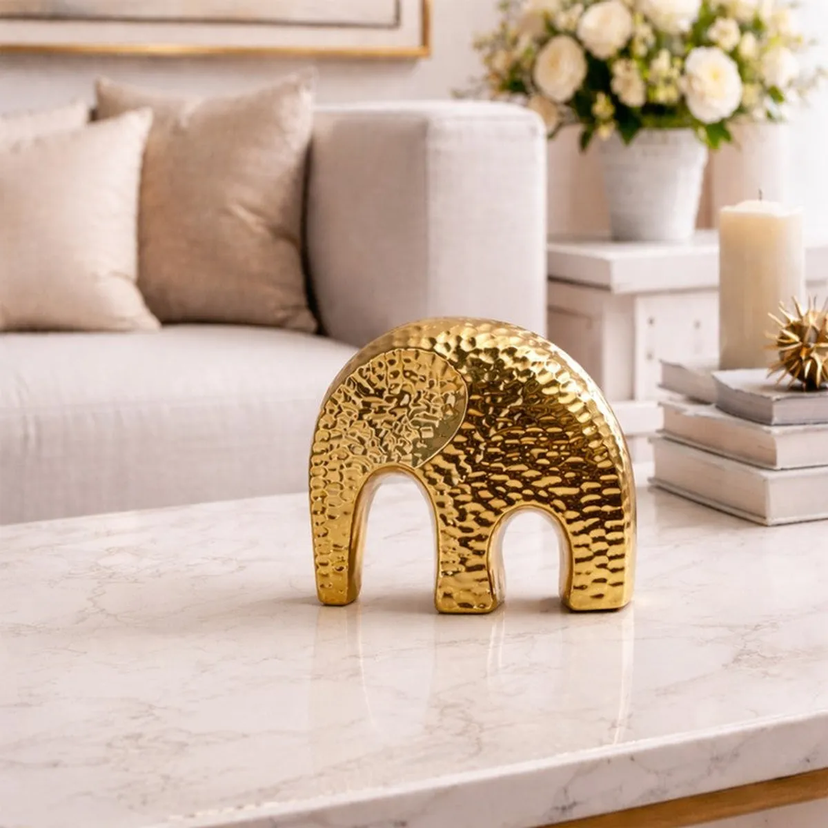 Gold elephant showpiece styled on a marble tabletop beside candles and flowers
