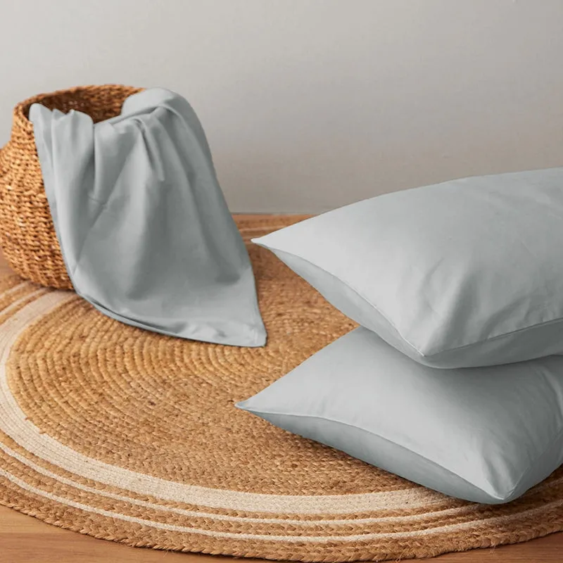 Light grey pillow covers arranged on a woven mat