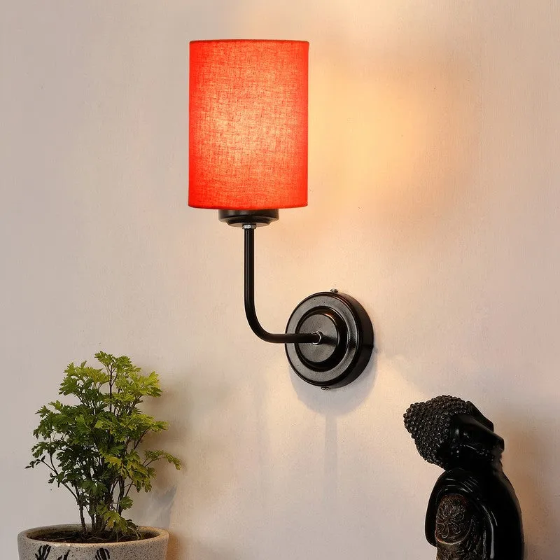 Lit orange wall lamp with black iron arm casting a warm glow