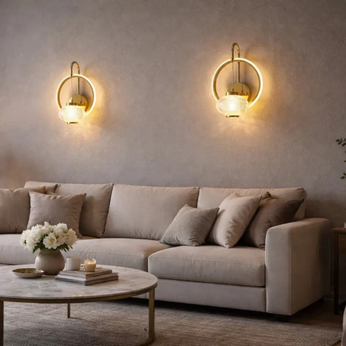 Two matching gold ring wall lamps glowing above a beige sofa.