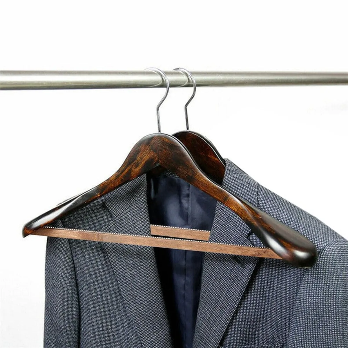 Close-up of brown wooden hanger with a grey blazer on a rail