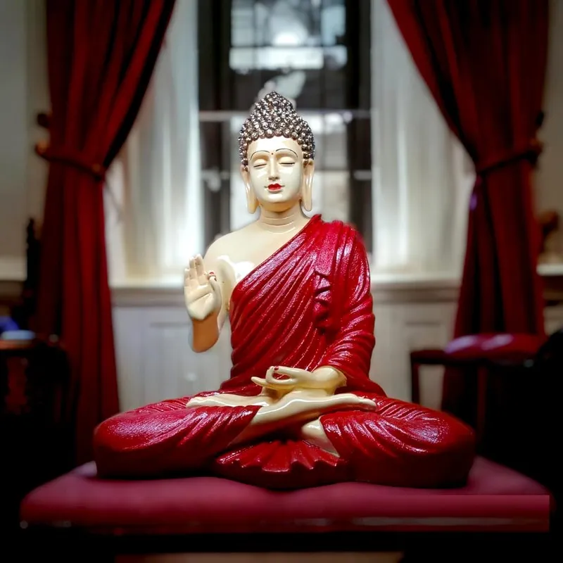 Front angled view of red Buddha idol placed indoors