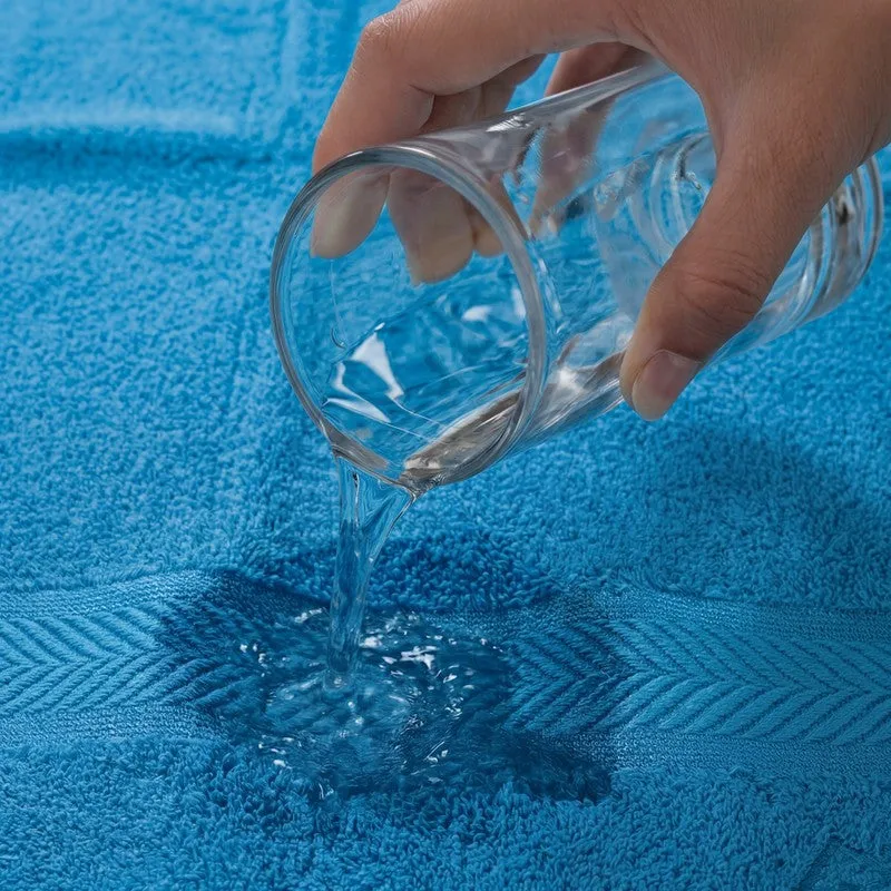 Water being poured onto a vivid blue bath towel