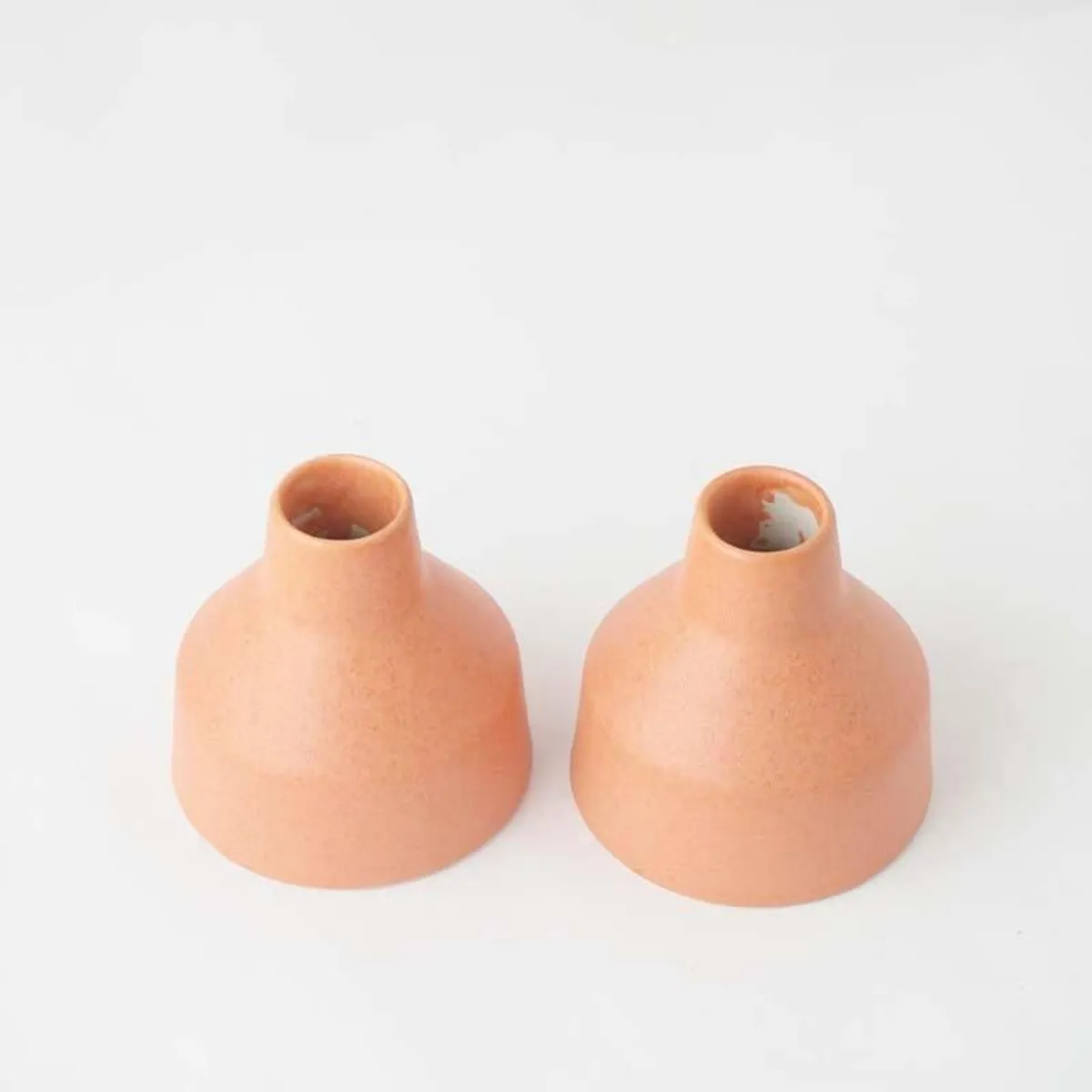 Top view of two blush pink ceramic vases on a white background