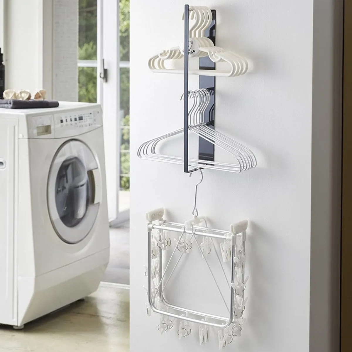 Black magnetic organiser mounted vertically with hangers in a laundry area