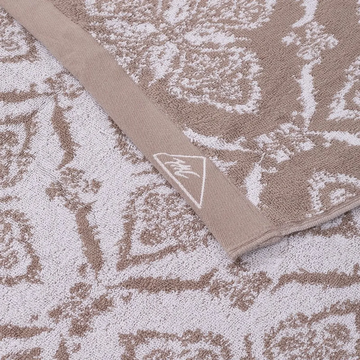 Close-up of beige and cream floral detailing on the towel border