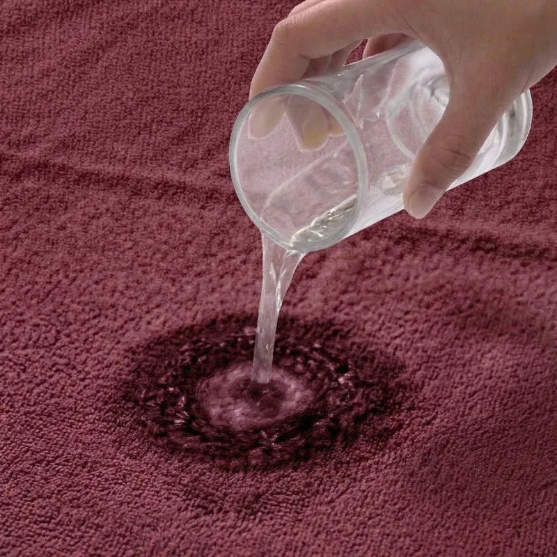 Water being poured onto the surface of a maroon towel