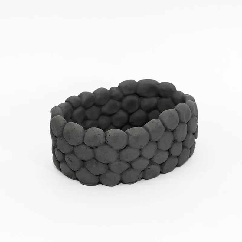 Angled view of a grey oval accent bowl with pebble-like textured sides
