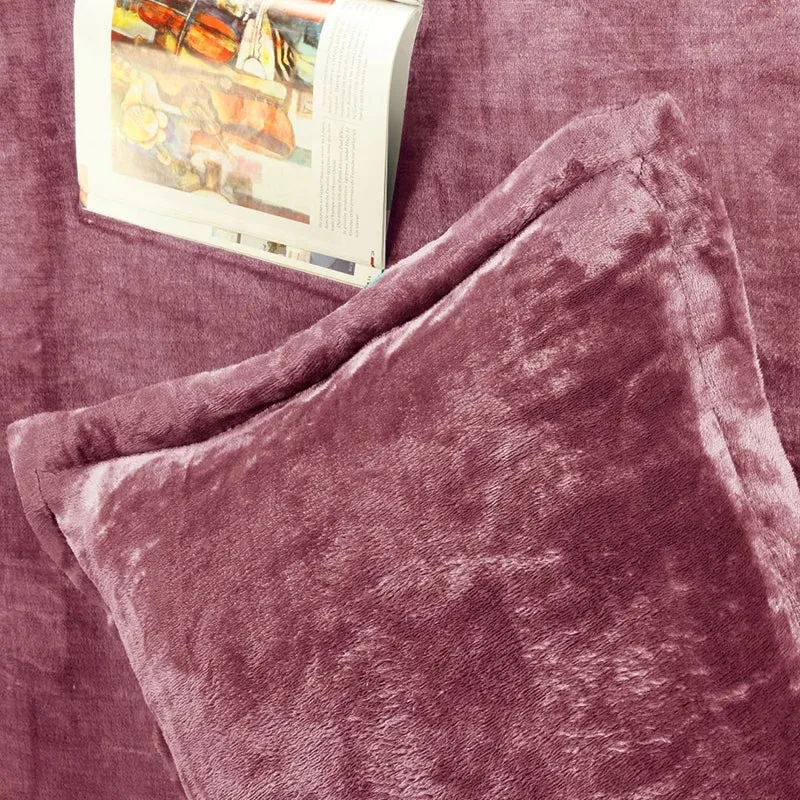 Pink velvet pillow cover on matching bedsheet with an open book