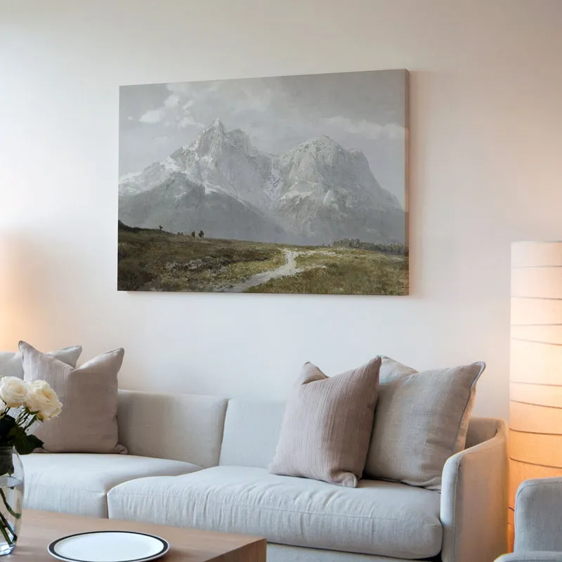 Scenic mountain wall art hung above a cream sofa with soft lighting