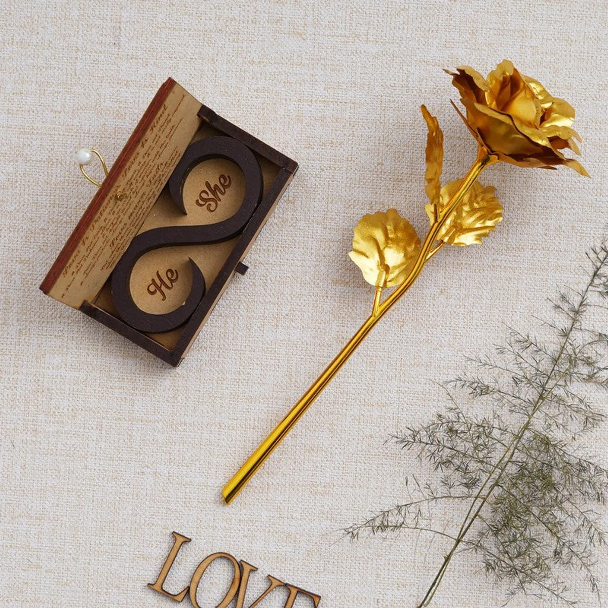 Open rectangular decorative box beside a golden rose