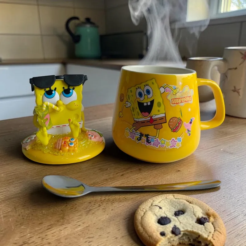 Yellow SpongeBob ceramic mug with figurine lid and spoon on a table