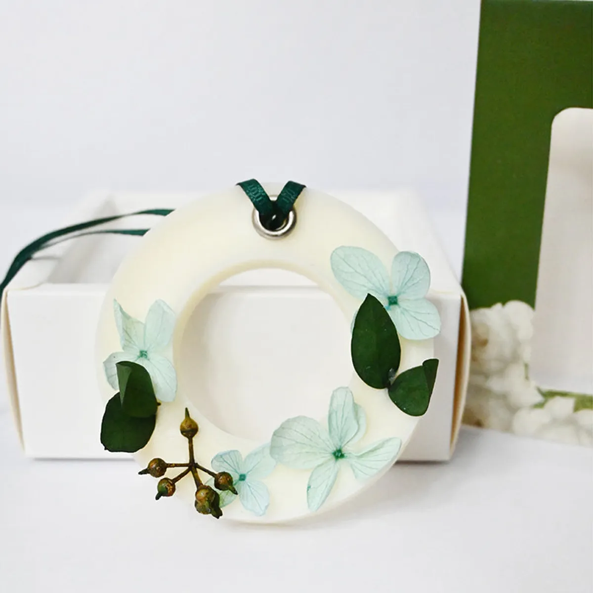 Close-up of round white floral wax melt with pale blue flowers and green leaves