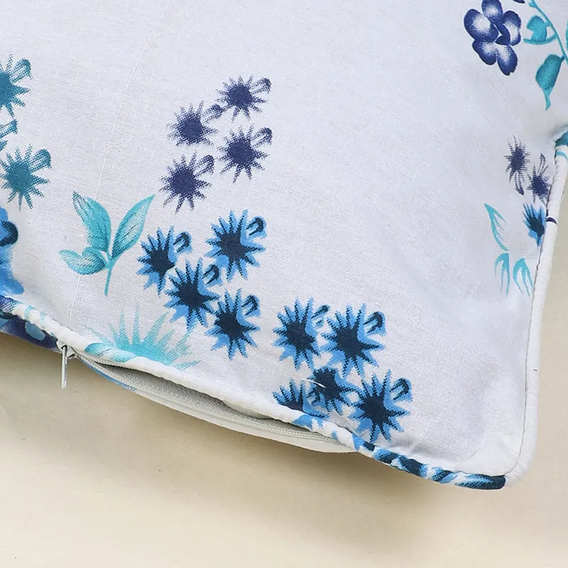 Close view of blue floral print, piped edge and zip on a white cushion cover