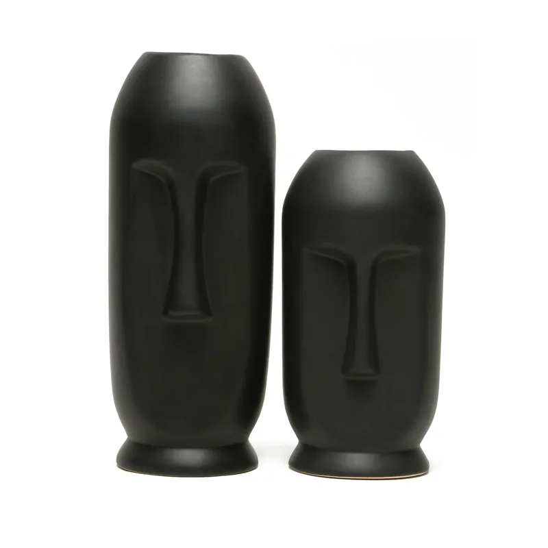 Tall and short matte black face vases displayed together on a white background.