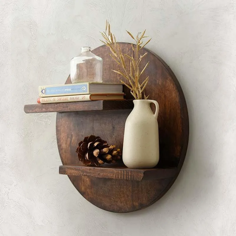Side view of a round brown wooden wall shelf with two ledges and decorative books and vase