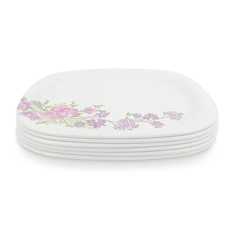 Stack of six white square floral dinner plates viewed from the side