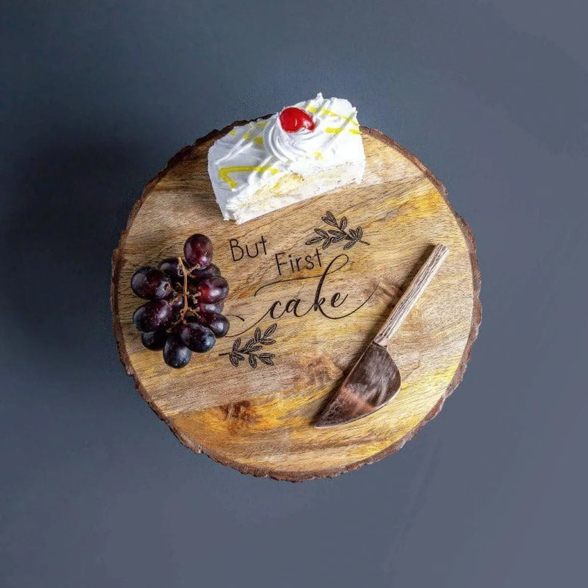 Top view of the mango wood cake stand with cake, grapes and But First Cake engraving