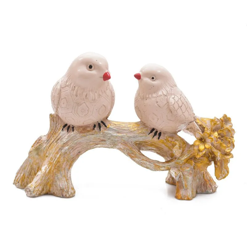 Front view of a pair of white birds on an ornate gold-toned branch.