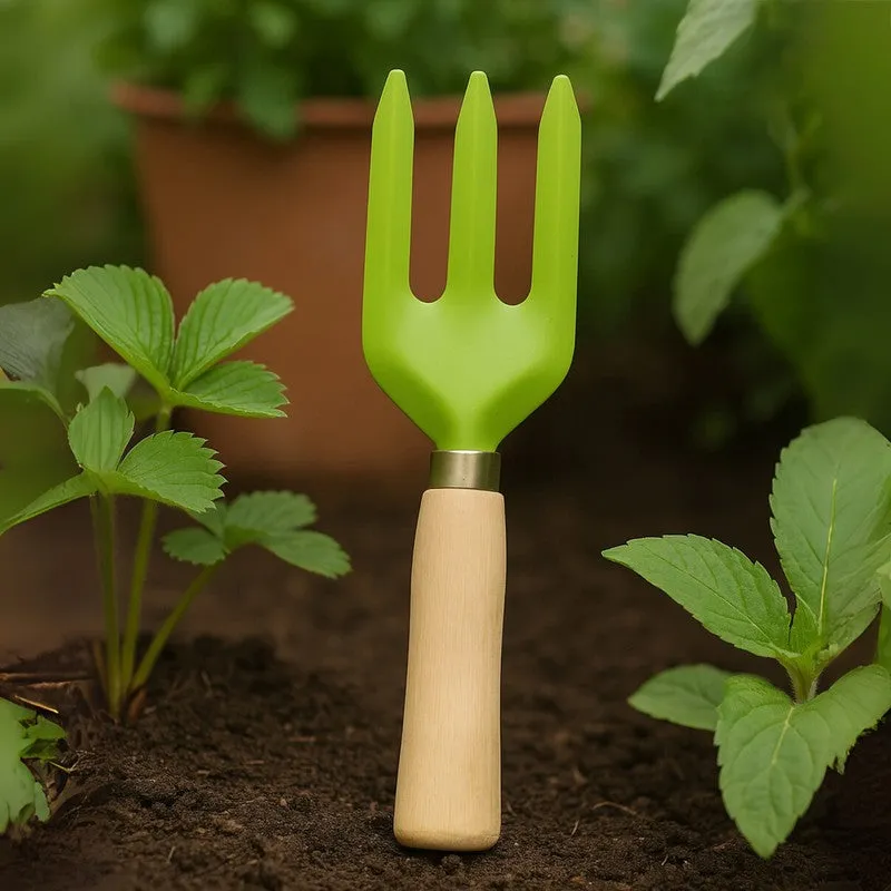 Green three-pronged garden fork standing upright among leafy garden plants