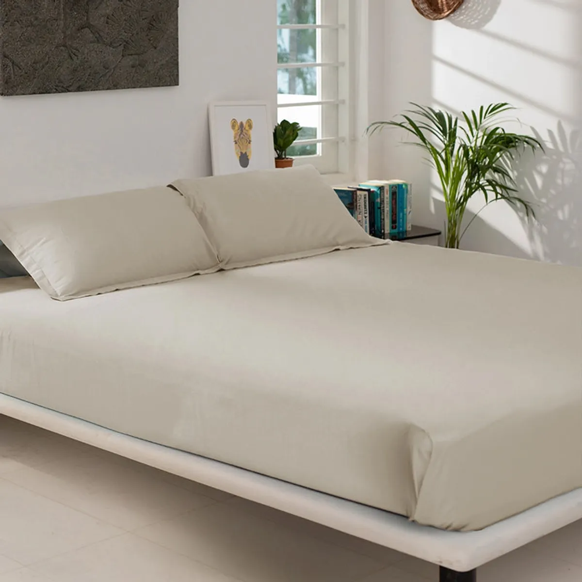 Beige fitted bedsheet neatly covering a bed with matching pillows