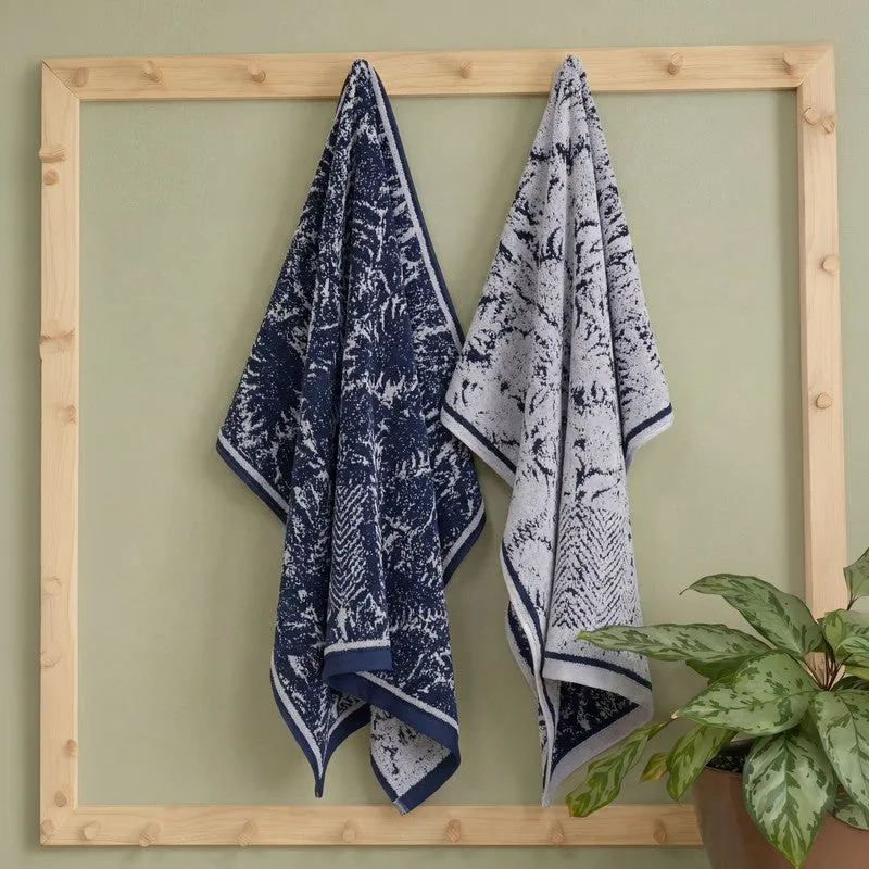 Blue and white patterned bath towels hanging on a wooden rack beside a leafy plant