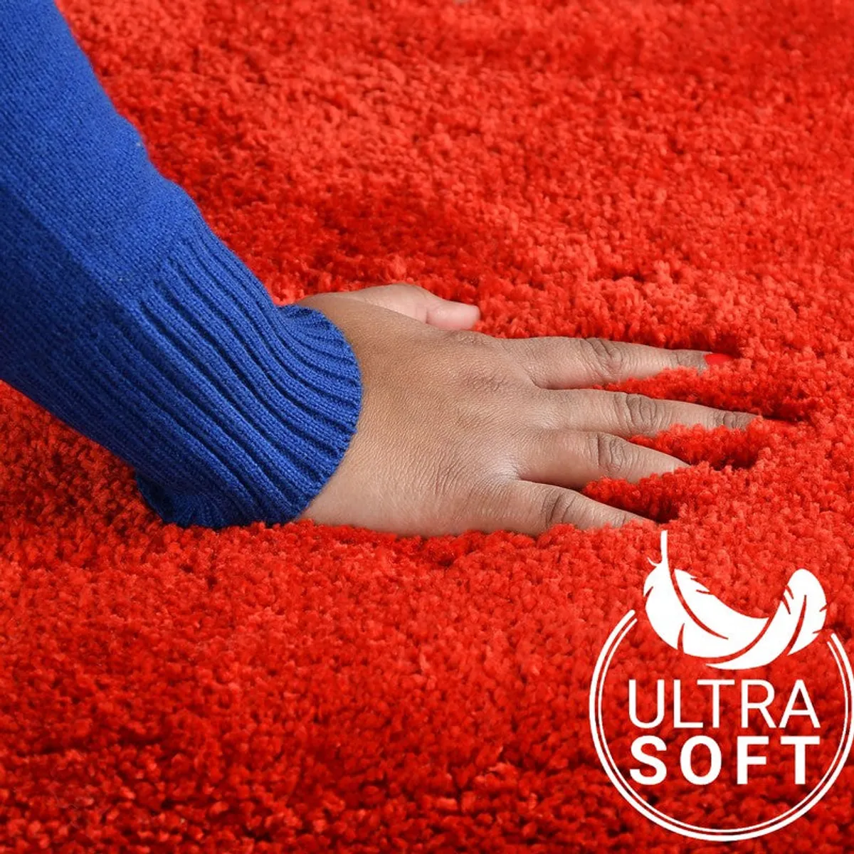 Hand pressing into the soft pile of a red bath mat
