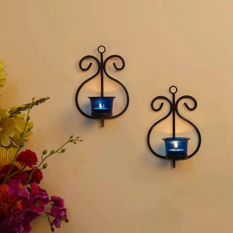 Two black wall sconces with blue glass cups styled on a wall