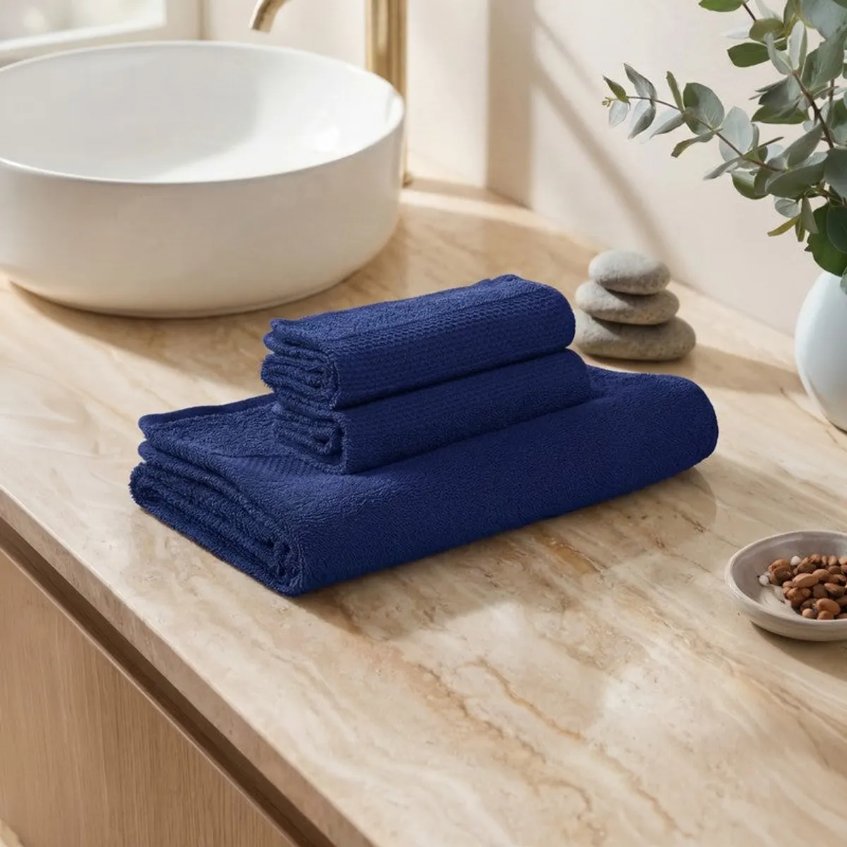Folded navy bath towel set placed on a bathroom counter
