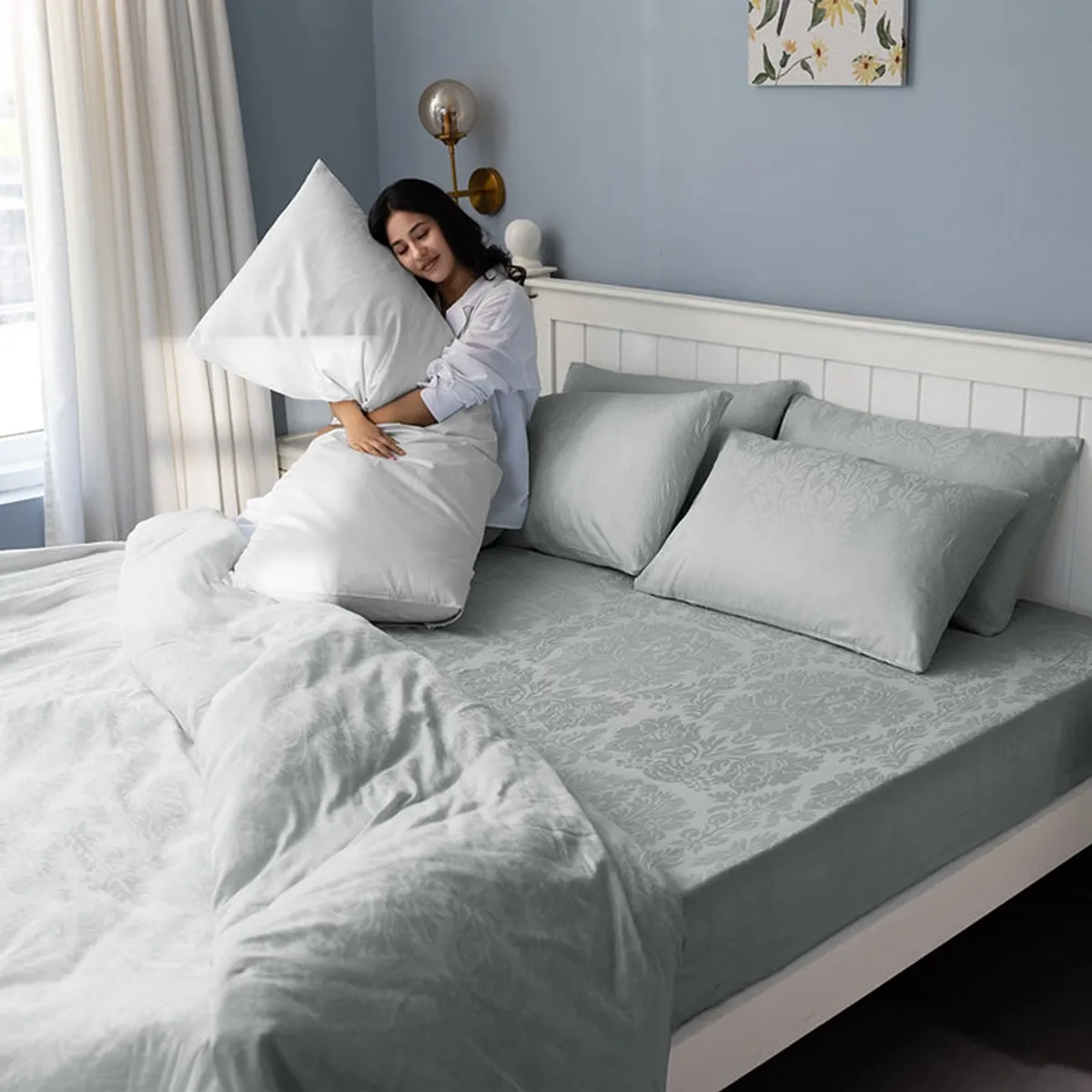 Person relaxing on a bed dressed in light grey floral bedding