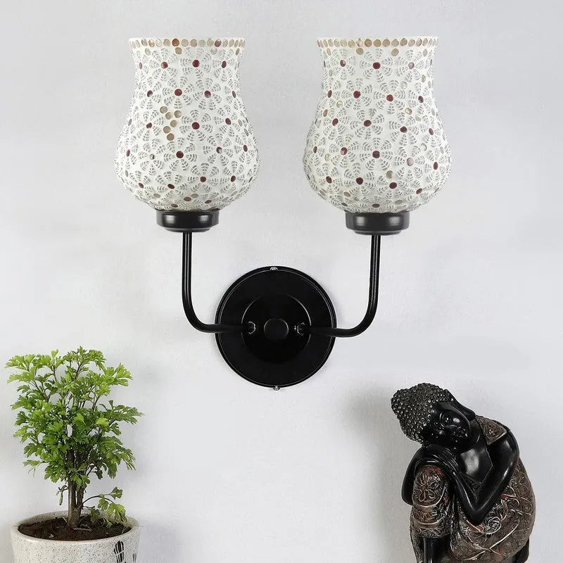 Unlit twin ivory mosaic glass wall lamp with black iron base on a white wall