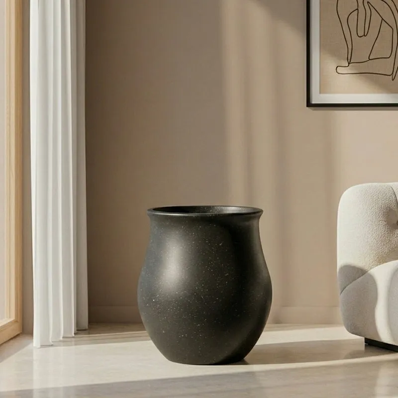 Black cylindrical planter shown empty in a contemporary living room