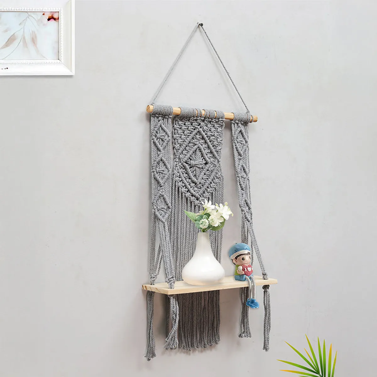 Grey macrame wall shelf styled with a vase and figurine